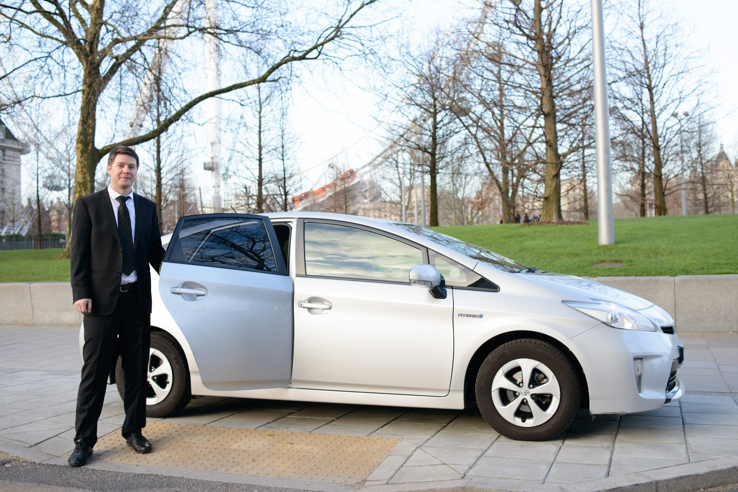 A photo of a saloon car with a driver standing in front of it.